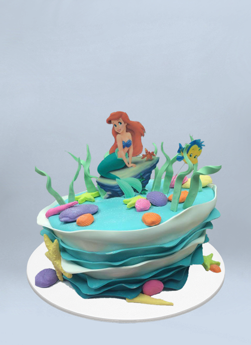 Photo: fondant topsy cake with waves and little mermaid Ariel sitting on top