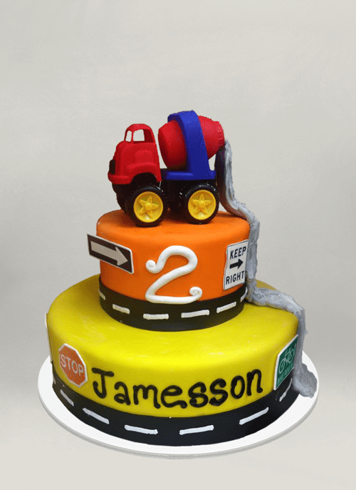Photo: fondant cake with 3d construction truck dripping cement down the two tiers, road signs around the tiers