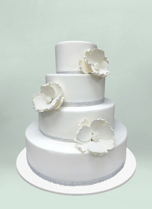 Photo: white fondant cake with large white flowers and gem ribbon on each tier